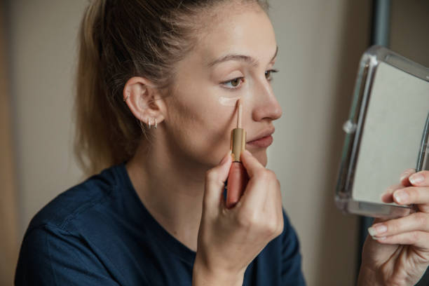 Close up, side view of a young female adult applying make up.